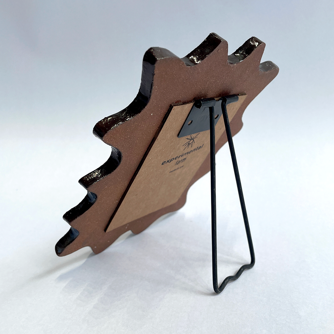 A rustic, abstract shaped ceramic picture frame with a black metal stand, displayed on a clean white background.